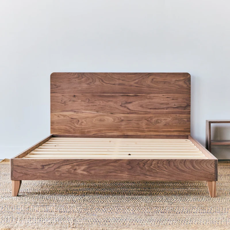 Wooden bed frame with a sleek walnut headboard and slatted base, showcasing organic materials in a minimalist design, ideal for Avocado mattresses.