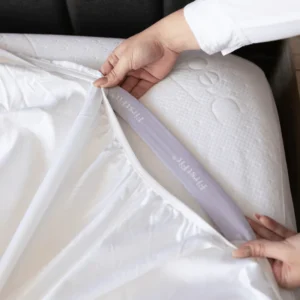 Hands placing a Dreamchill mattress protector on a mattress, showcasing its protective features and fit for twin-size bedding.