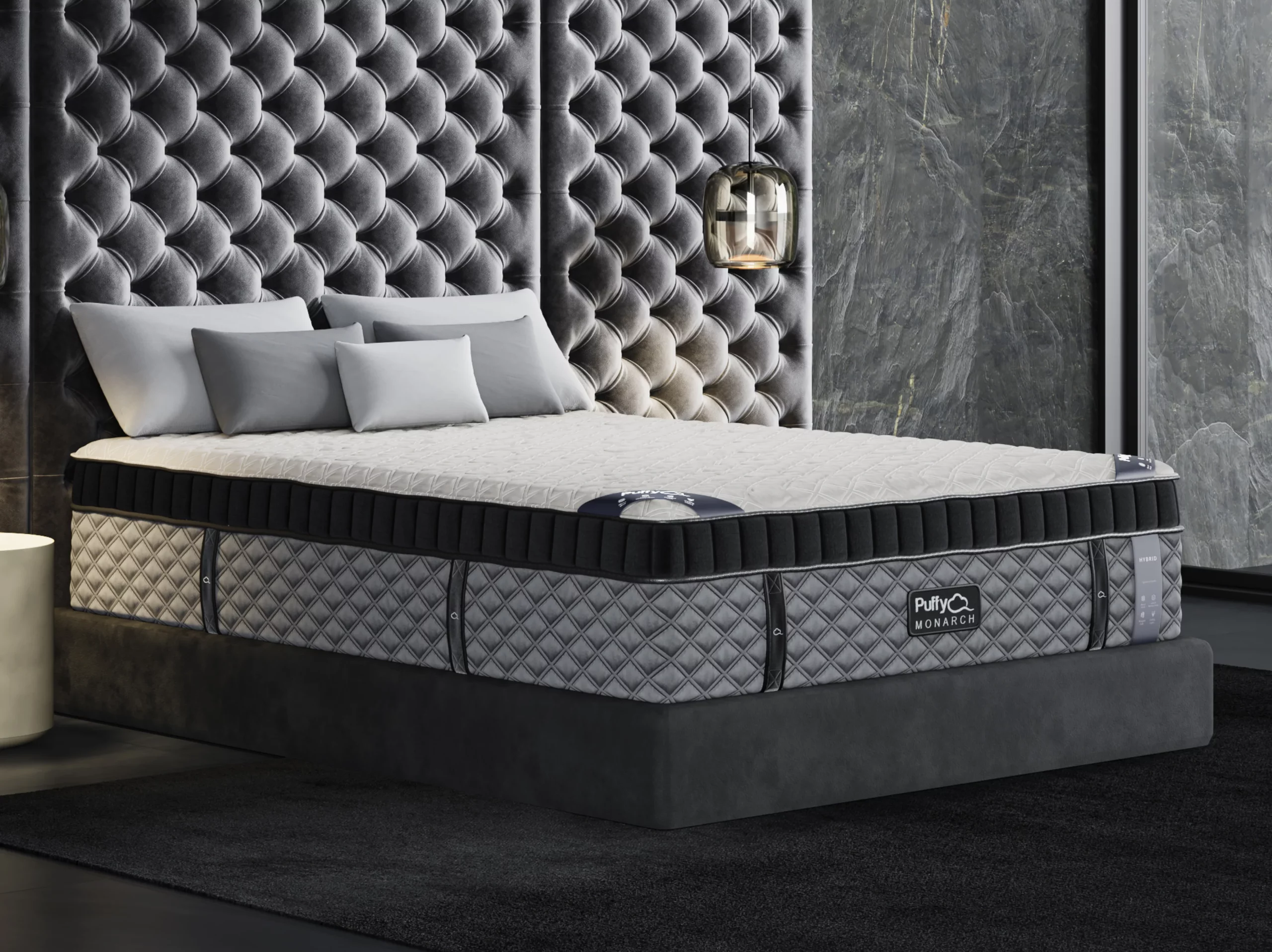 Puffy Monarch Hybrid 2.0 mattress on a stylish platform bed with decorative pillows, featuring a quilted cover and a modern backdrop, emphasizing luxury comfort and chiropractic support.