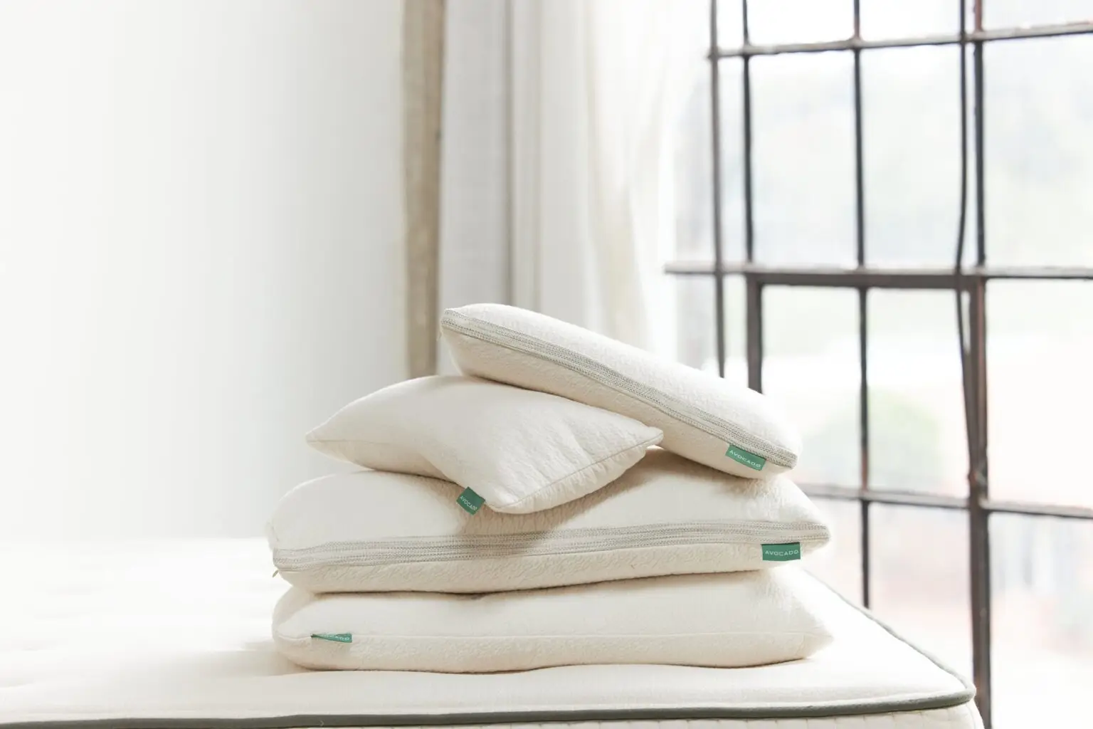 Stack of neutral pillows on a bed in a bright, modern bedroom